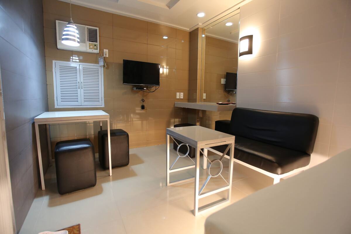 A modern room with a sofa, a small table, a TV, and a mirror.