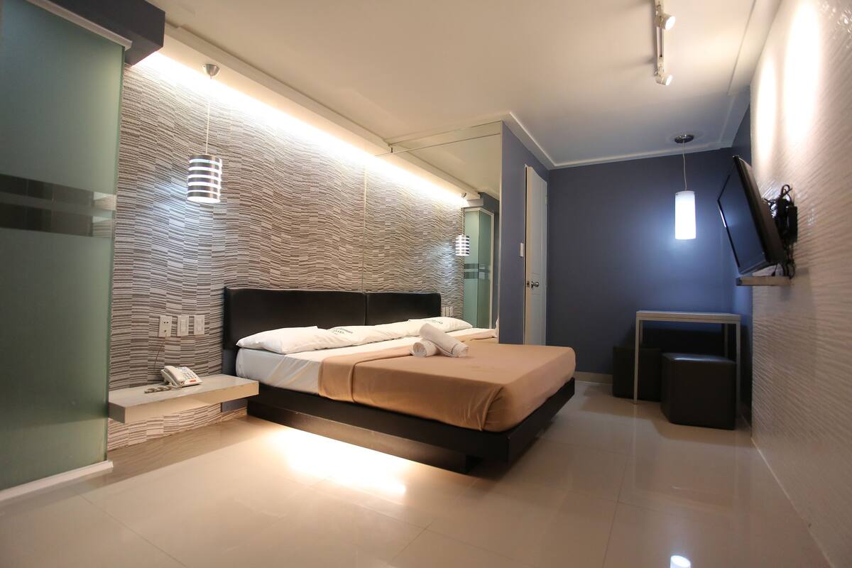 A modern bedroom with a bed, bedside table, and a wall-mounted TV.