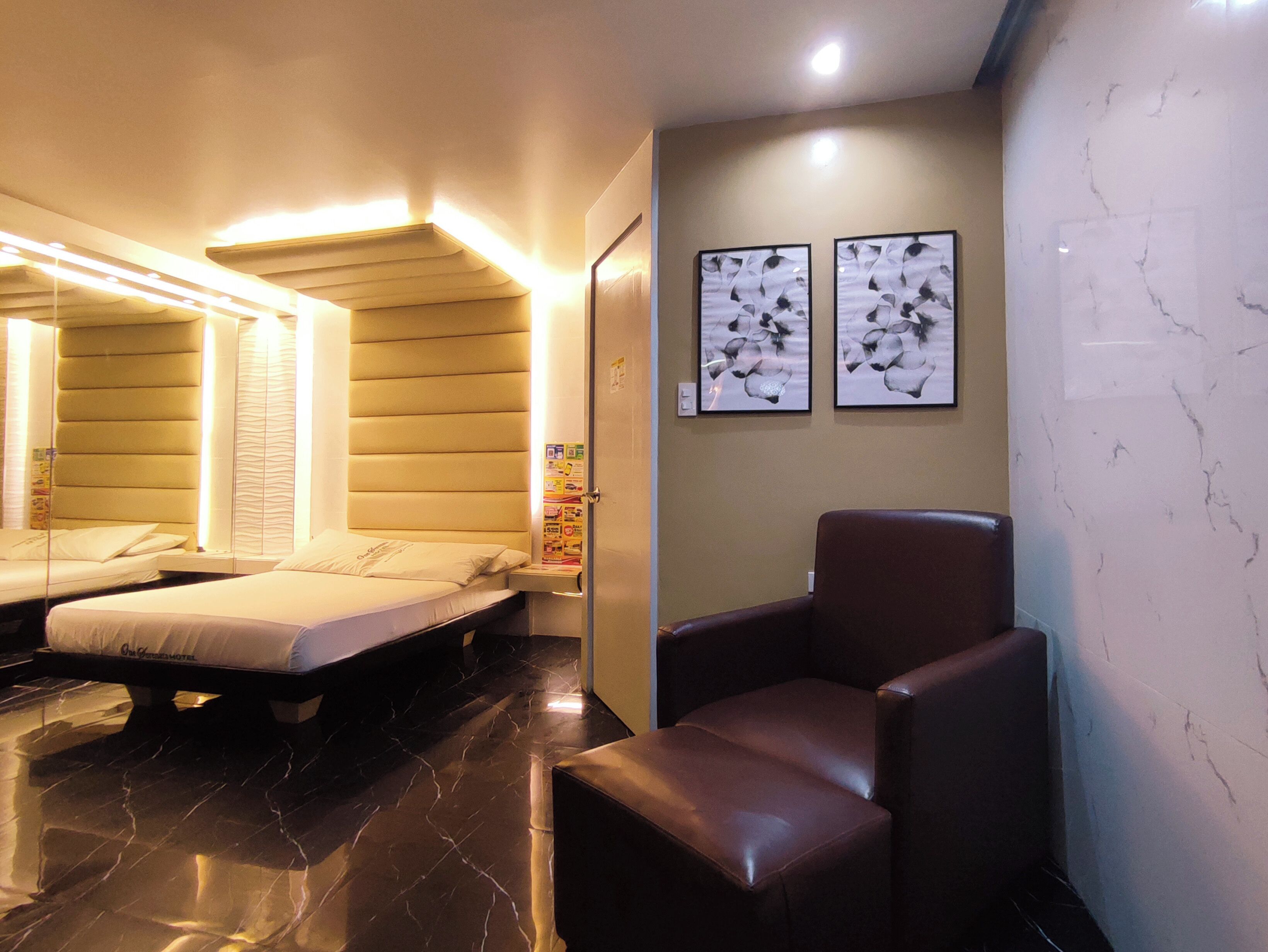 Une chambre d’hôtel avec un lit, une chaise et deux œuvres d’art encadrées accrochées au mur.