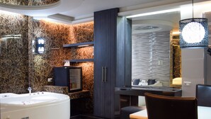 A modern bathroom with a large bathtub, a vanity with a mirror, and a seating area with a chair. - One Serenata Hotel Bacoor (Bacoor City)
