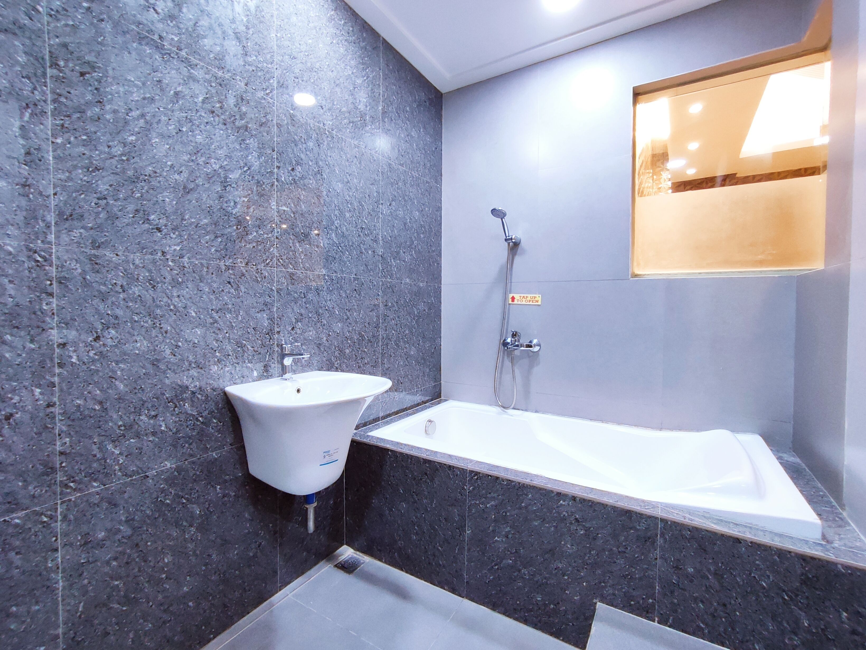 A modern bathroom with a marble wall, a sink, and a bathtub.