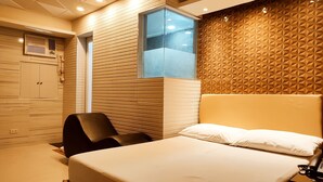 A hotel room with a bed, a chair, a wardrobe, and a window. - One Serenata Hotel Bacoor (Bacoor City)