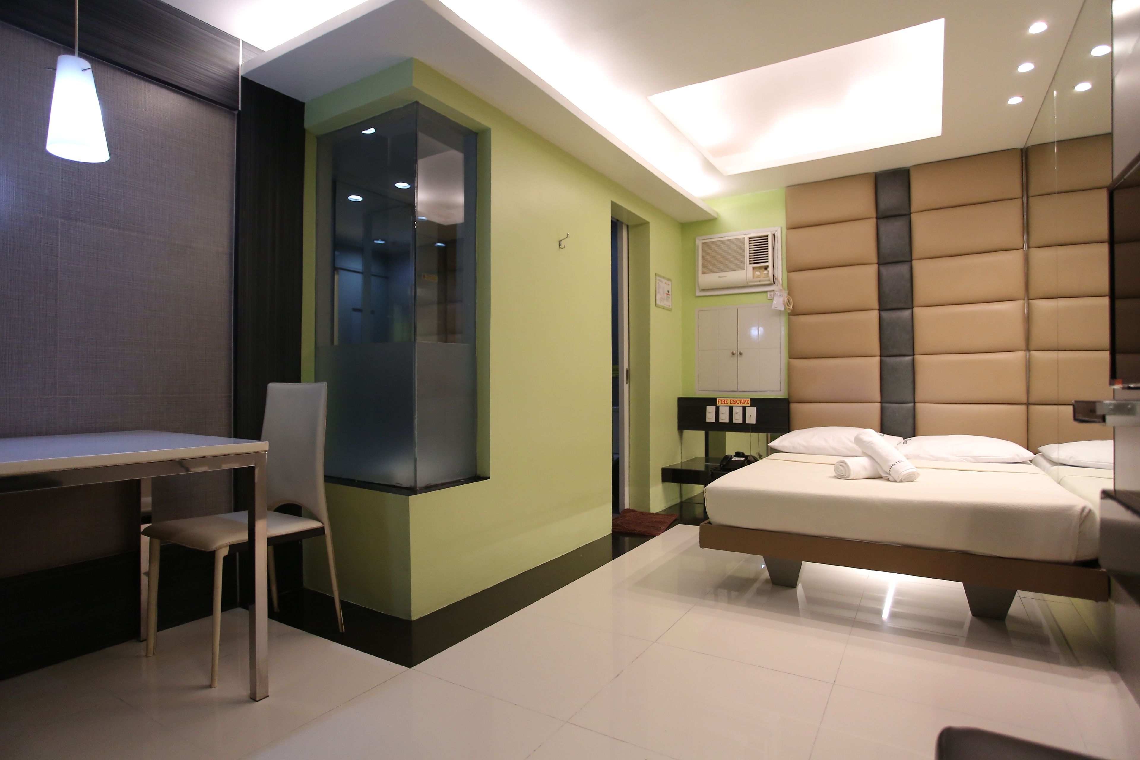 A modern hotel room with a bed, a desk, and a chair.