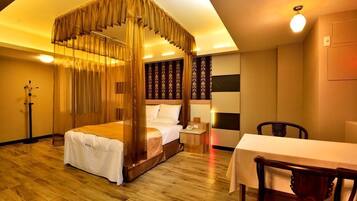 A bedroom with a four-poster bed, a bedside table, a nightstand, and a dining table with chairs.