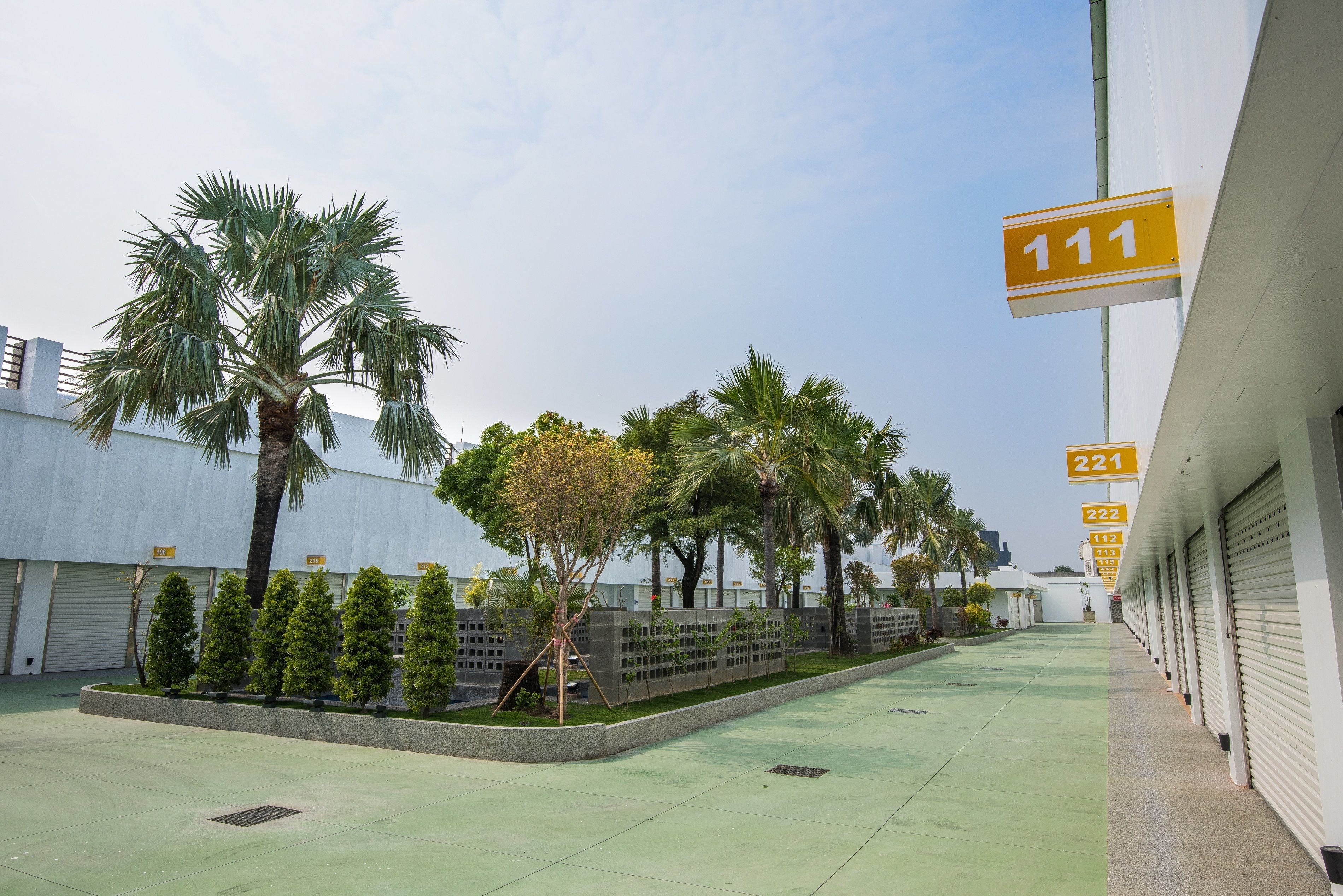 A parking area with numbered parking spaces, palm trees, and a building with garage doors.