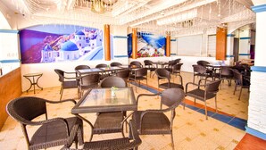 A restaurant with wicker furniture, a mural of a coastal town, and a ceiling with hanging lights. - Dreamwave Hotel Puerto Galera (Puerto Galera)