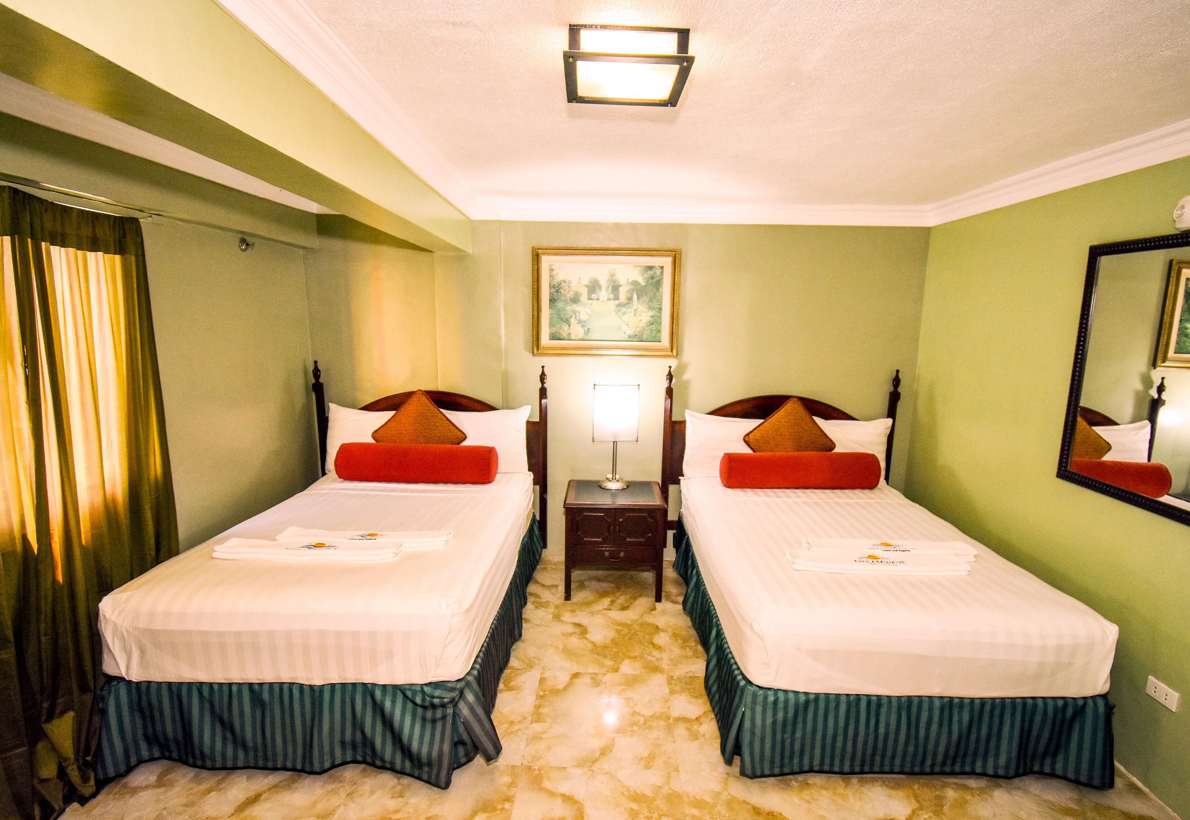 Habitació d'hotel amb dos llits, una tauleta de nit, una làmpada, un quadre a la paret i un mirall.