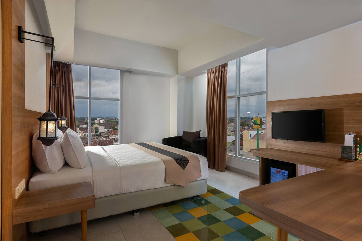 Ein modernes Hotelzimmer mit einem großen Bett, einem Fernseher und Blick auf die Stadt.