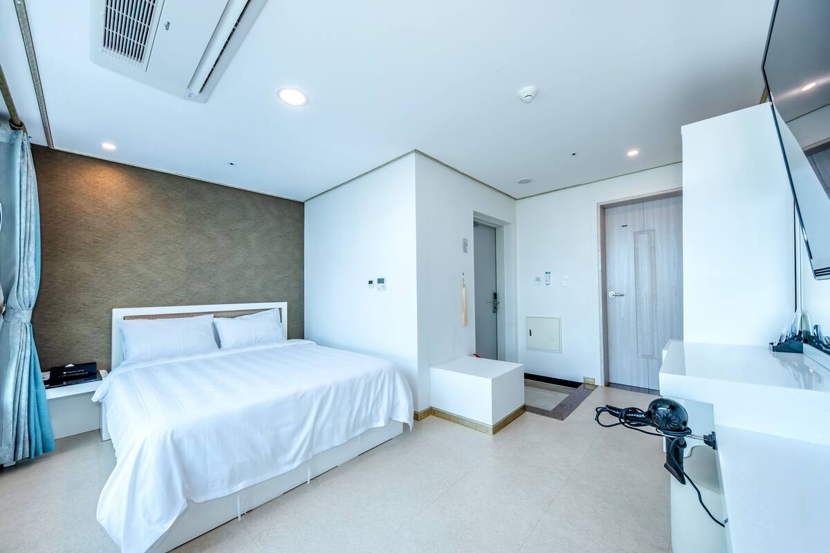 Ein modernes Hotelzimmer mit einem großen Bett, einem Nachttisch und einer integrierten Bank.