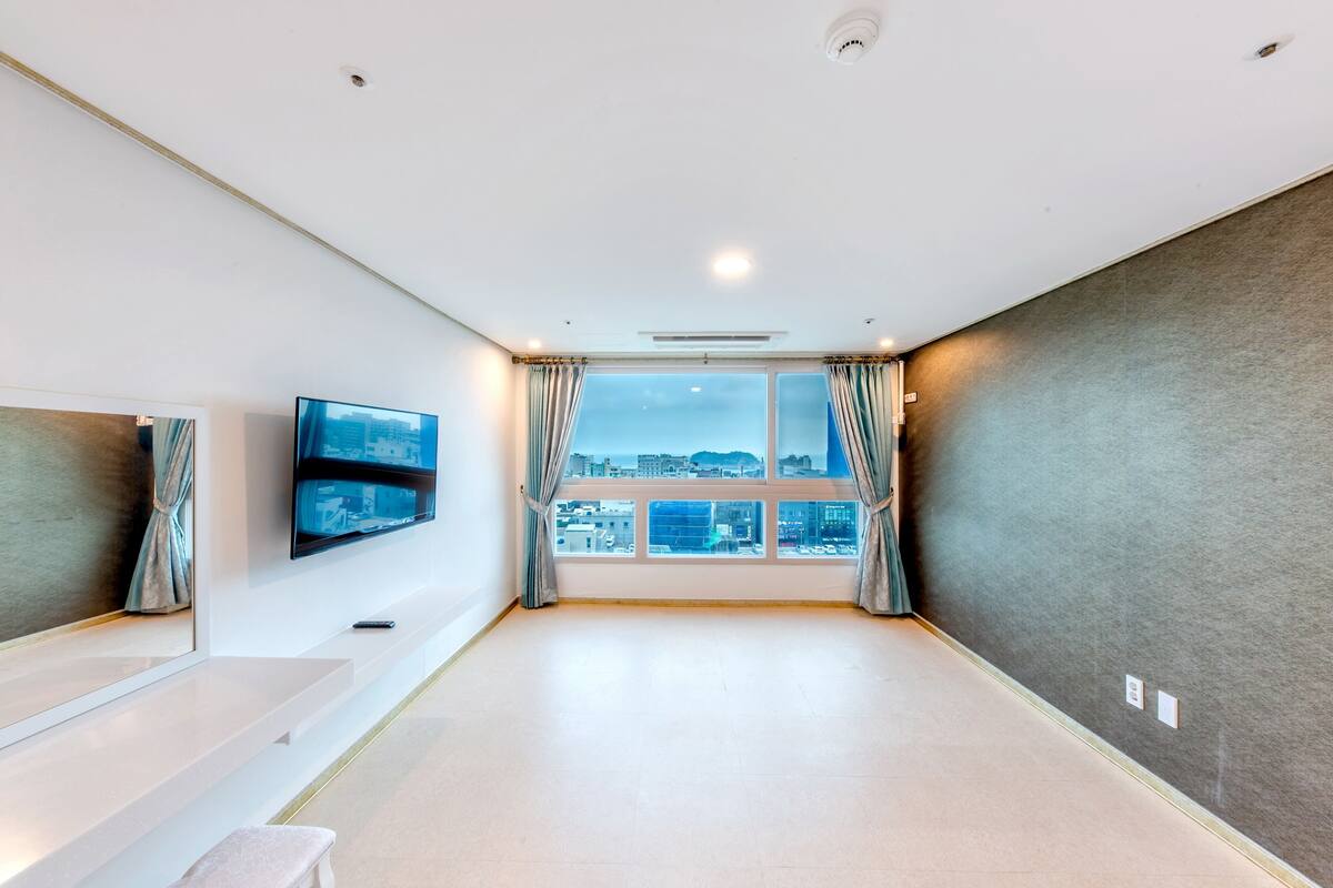 Ein modernes Hotelzimmer mit großem Fenster, Flachbildfernseher und einer Bank.