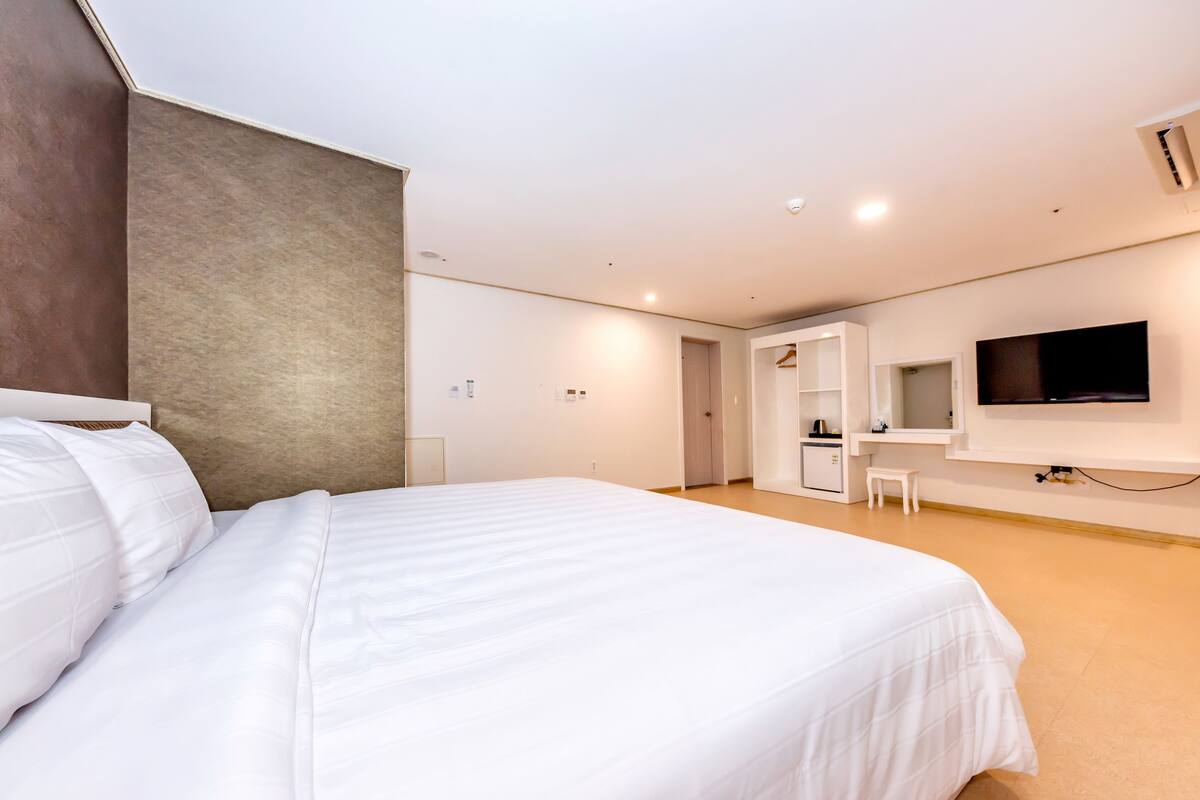 Ein modernes Hotelzimmer mit einem großen Bett, einem Schreibtisch, einem Fernseher und einer Küchenzeile.