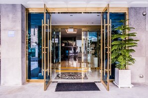 Ein Hotel mit Eingang, Glastüren, einer Rezeption und einem großen Topfpflanzenarrangement.