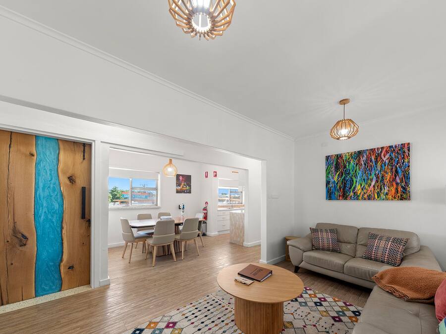 A modern living room with a sofa, coffee table, and a colorful abstract painting.
