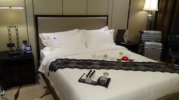 Une chambre d’hôtel avec un lit, une table de chevet avec un téléphone, une lampe et une valise.