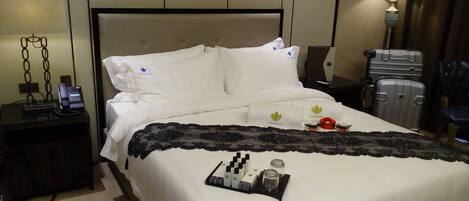 A hotel room with a bed, a bedside table with a phone, a lamp, and a suitcase.