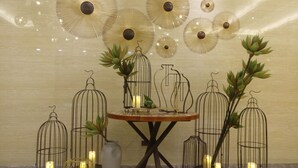 Una mesa con decoraciones de jaulas de pájaros y velas, rodeada de arte en la pared y un florero.