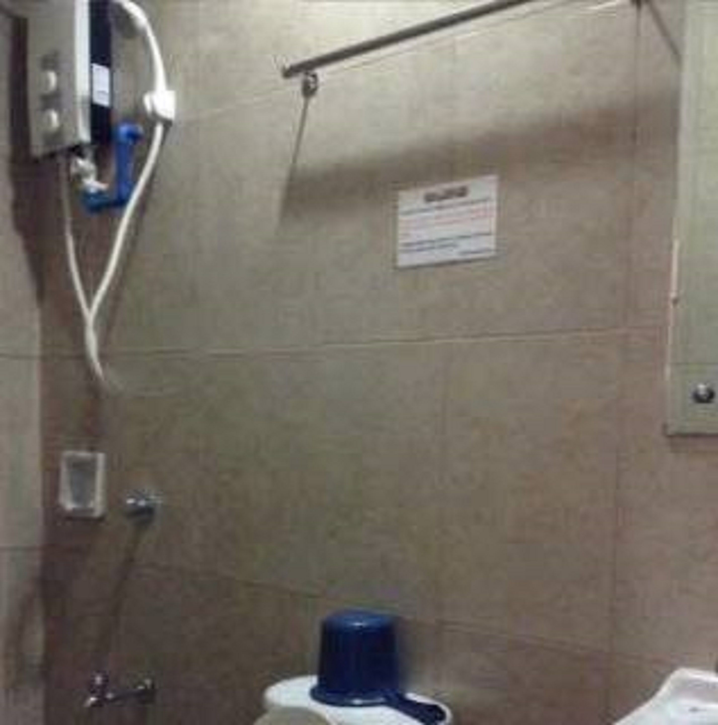 Une salle de bain équipée d’un sèche-mains, d’un distributeur de serviettes et d’une pancarte au mur.