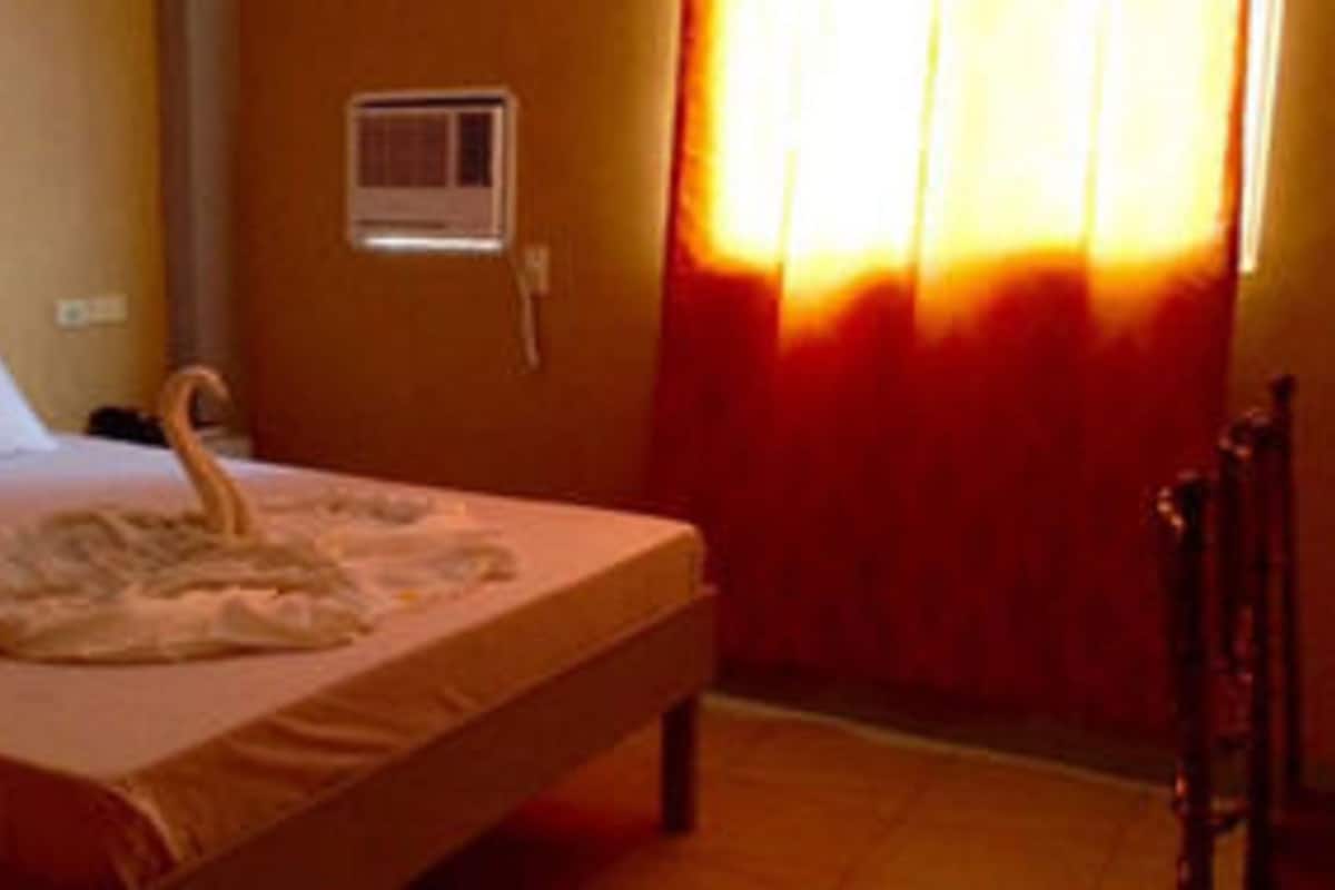 A bed with a swan-shaped pillow and a small air conditioning unit on the wall.
