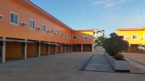 A courtyard with a series of orange buildings, a central staircase, and a planter with greenery. - UKL Ever Resort Hotel (Laoag)