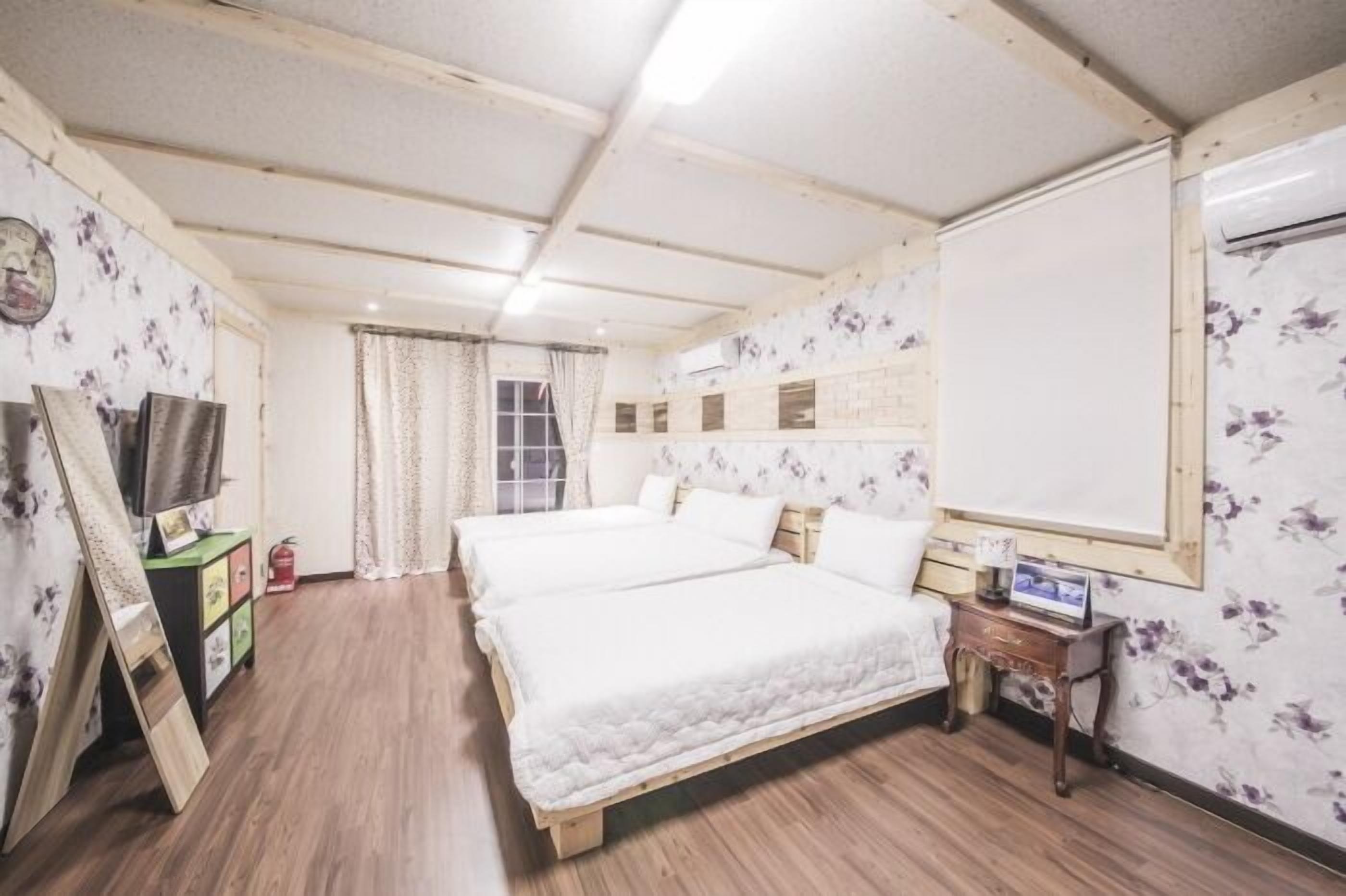 A room with two beds, a TV, a small table, and a whiteboard.