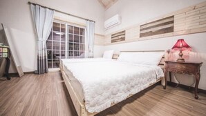 A bedroom with a wooden bed, a window with curtains, a nightstand with a lamp, and a wooden floor. - Red Windmill Pension (Jeju City)