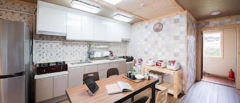 A compact kitchen with white cabinets, a wooden dining table, and a small window.