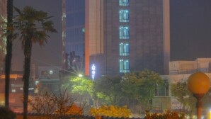 A tall hotel building with illuminated signage at the top. - Eins Hotel (Seogwipo)