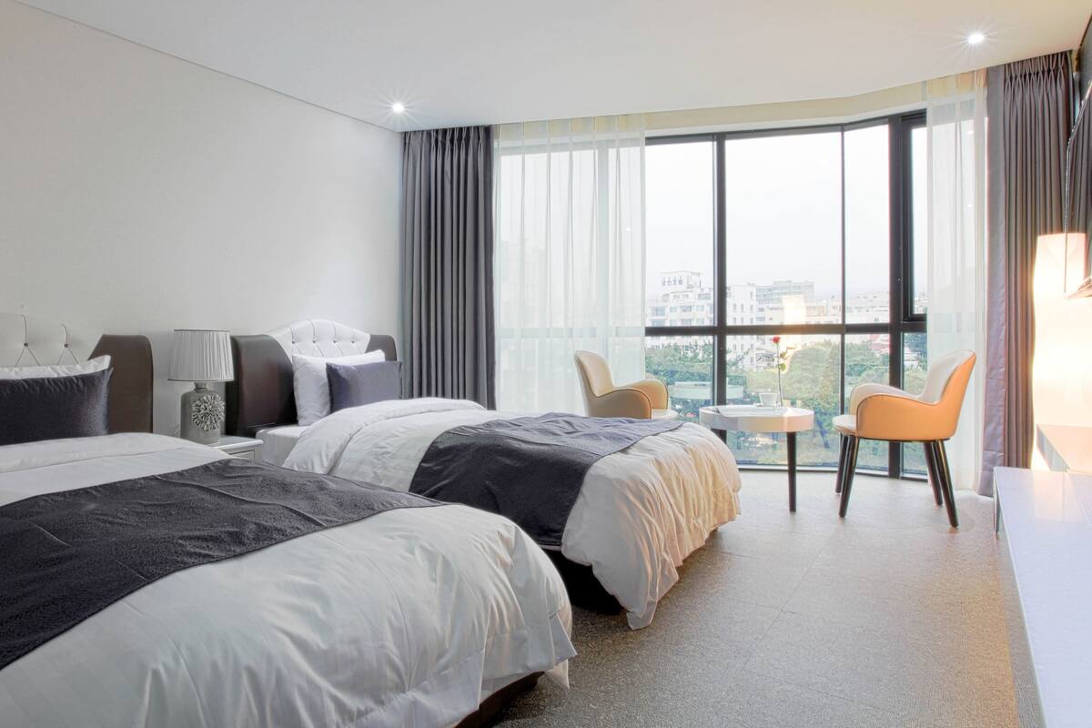 Une chambre d’hôtel avec deux lits, un bureau et une chaise.