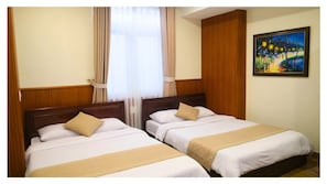 A hotel room with two beds, wooden paneling, a painting on the wall, and a window with curtains.