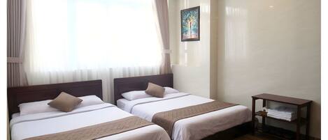 A hotel room with two beds, a nightstand, and a painting on the wall.