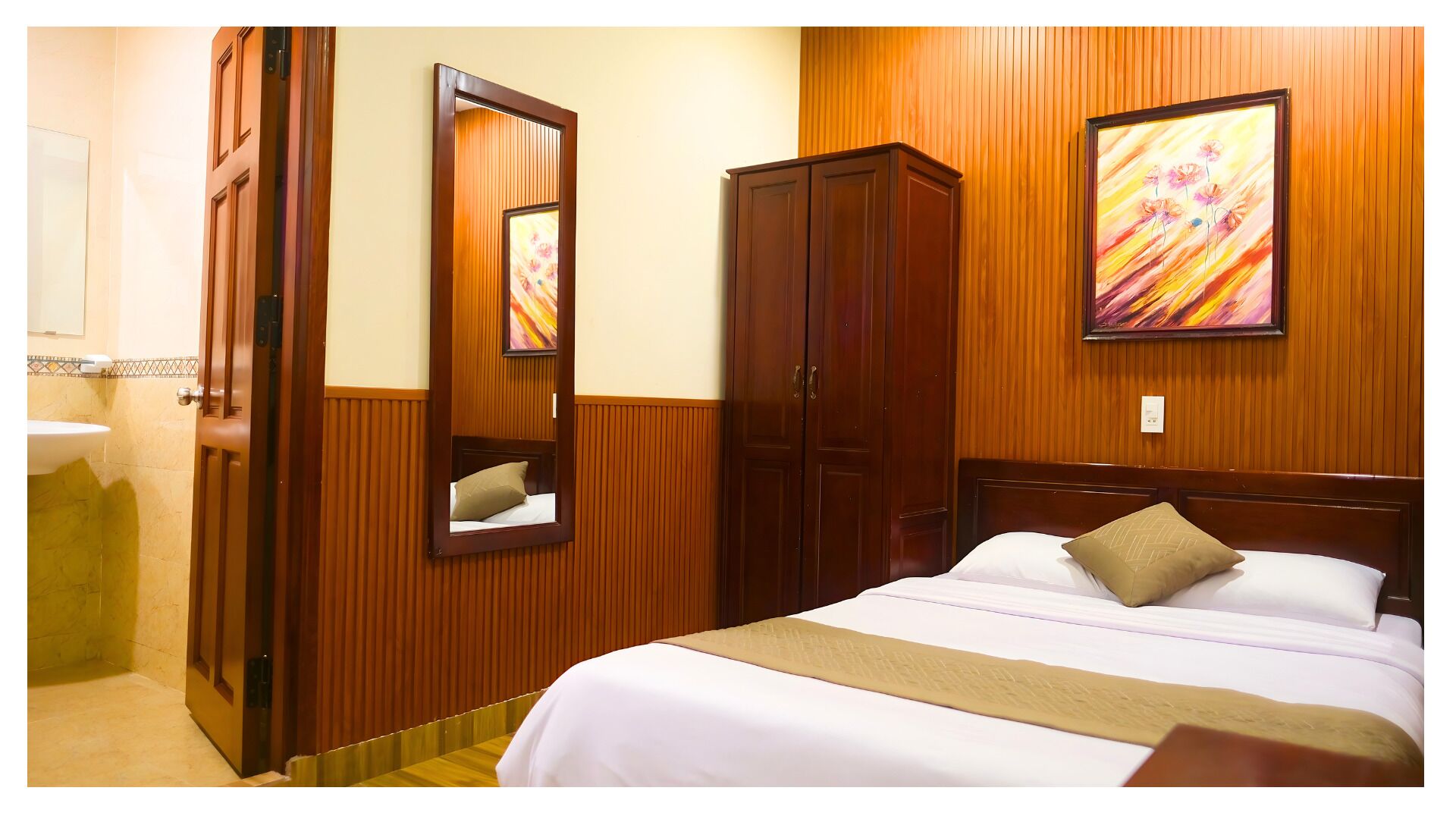 Ein Hotelzimmer mit Bett, Schrank, Spiegel, einem Bild und einem Badezimmer.