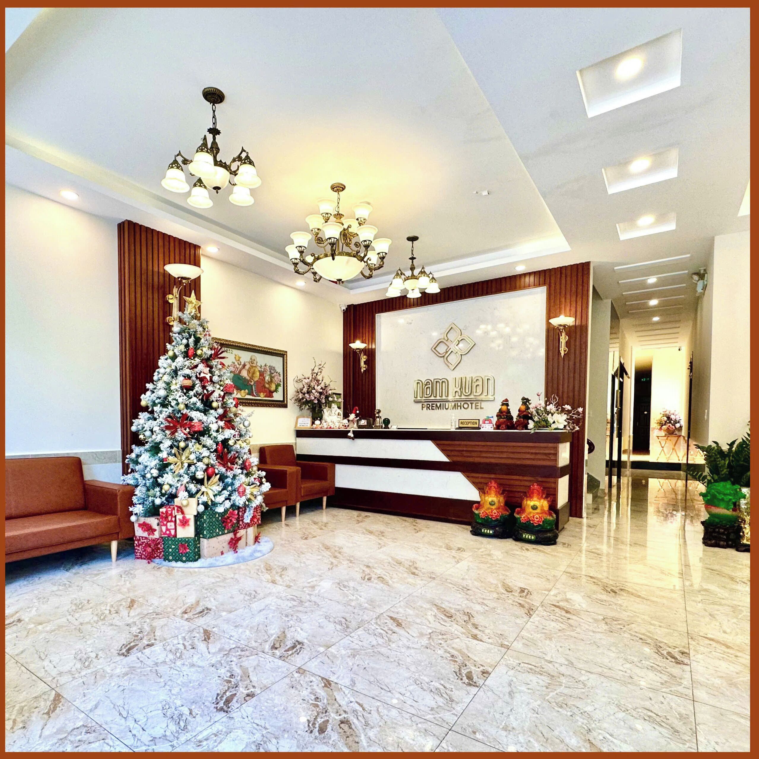 A hotel reception area with a Christmas tree, a reception desk, and a chandelier.