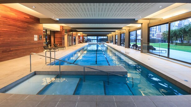 A swimming pool with a view of the city through large windows. - Mono Apartments on Freshwater (Southbank)