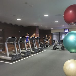 A gym with treadmills, exercise balls, and a television screen in the background. - Mono Apartments on Freshwater (Southbank)