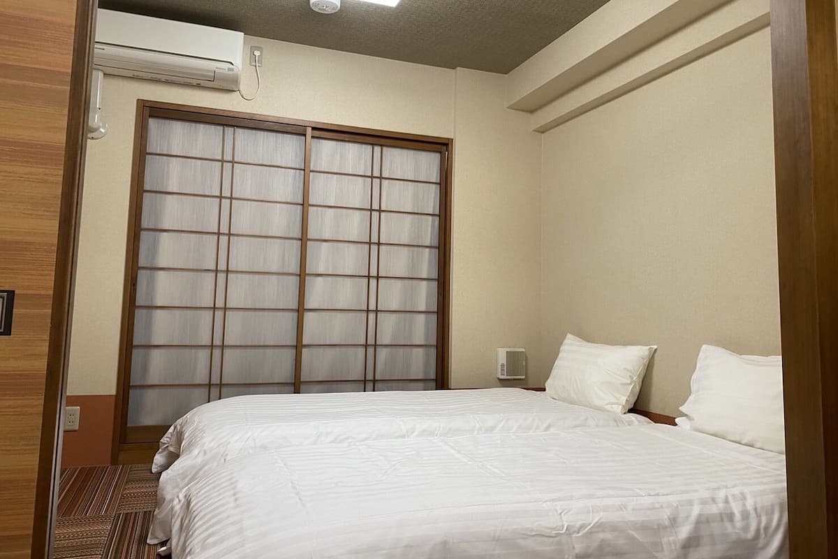 A hotel room with a bed, a large sliding door, and a ceiling light.