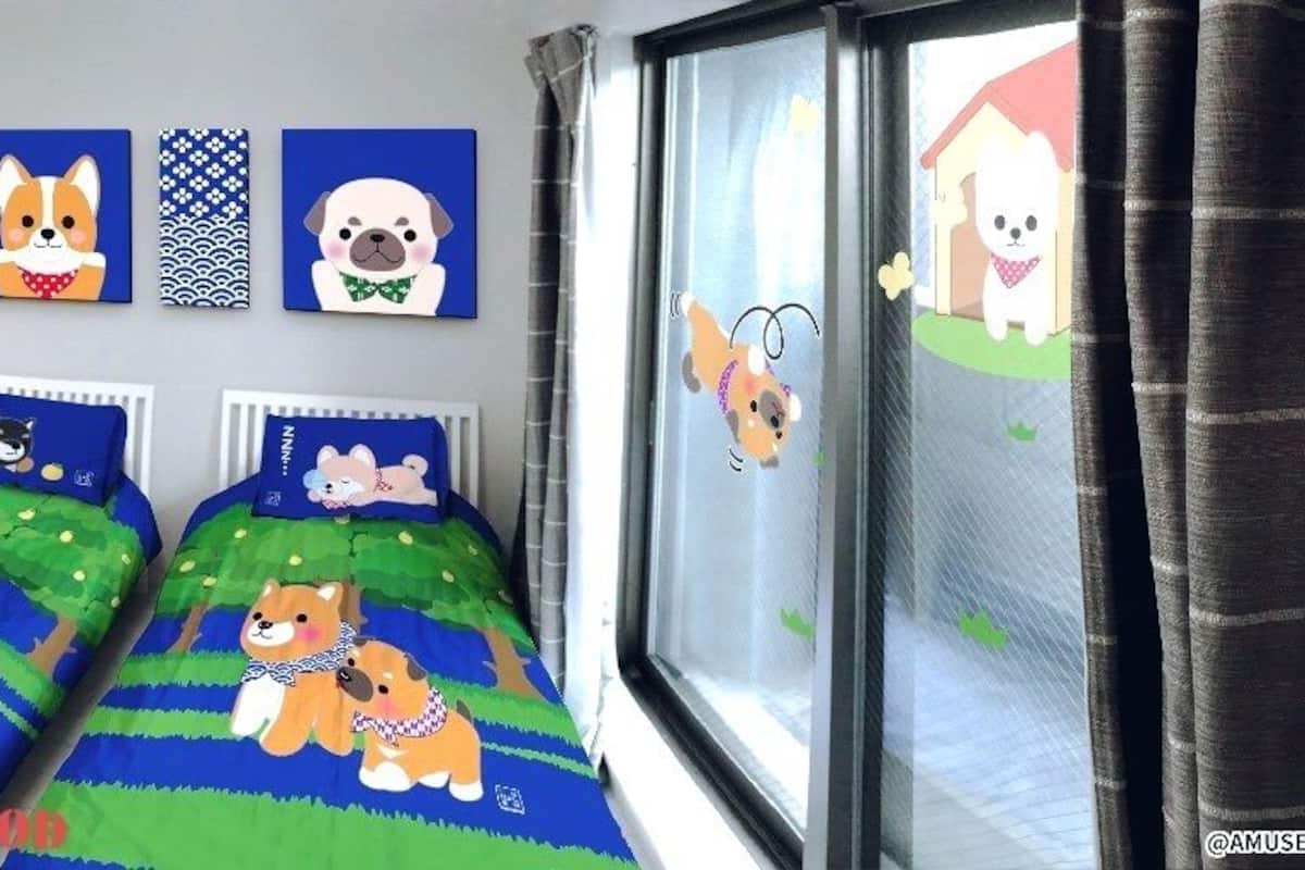 A room with two beds, a desk, and a chair. There are wall decorations including framed pictures and a wall clock.