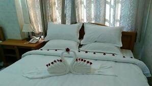 Une chambre d’hôtel avec un lit bien fait, un téléphone sur la table de chevet et des rideaux.