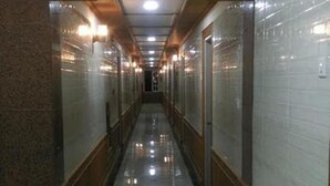 Un long couloir étroit doté d’un sol en marbre poli, de lambris en bois sur les murs et d’un plafond pourvu d’un éclairage encastré.