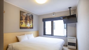 Habitación de hotel con una cama grande, un ventanal con vistas, un cuadro en la pared y un ventilador de techo.
