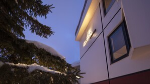 Un edificio con techo nevado y una ventana con una lámpara.