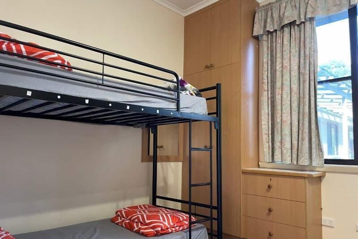 Habitación con literas, armario de madera y un escritorio pequeño.