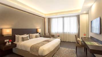 A hotel room with a large bed, a desk, and a TV.