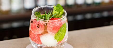 A clear glass with a layered drink, garnished with mint leaves, on a coaster.