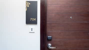 Una puerta de madera con un teclado numérico y una placa de números en la pared que muestra el número 704.