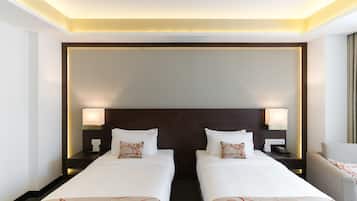 A hotel room with two single beds, nightstands with lamps, a headboard, and a chair.