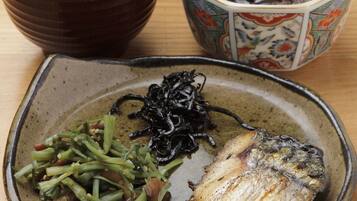 Una comida tradicional japonesa con pescado, verduras y arroz, servida en un plato de cerámica.