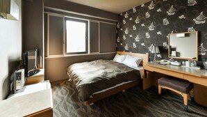 Una habitación de hotel con cama, escritorio con teléfono, espejo y ventana con persianas.