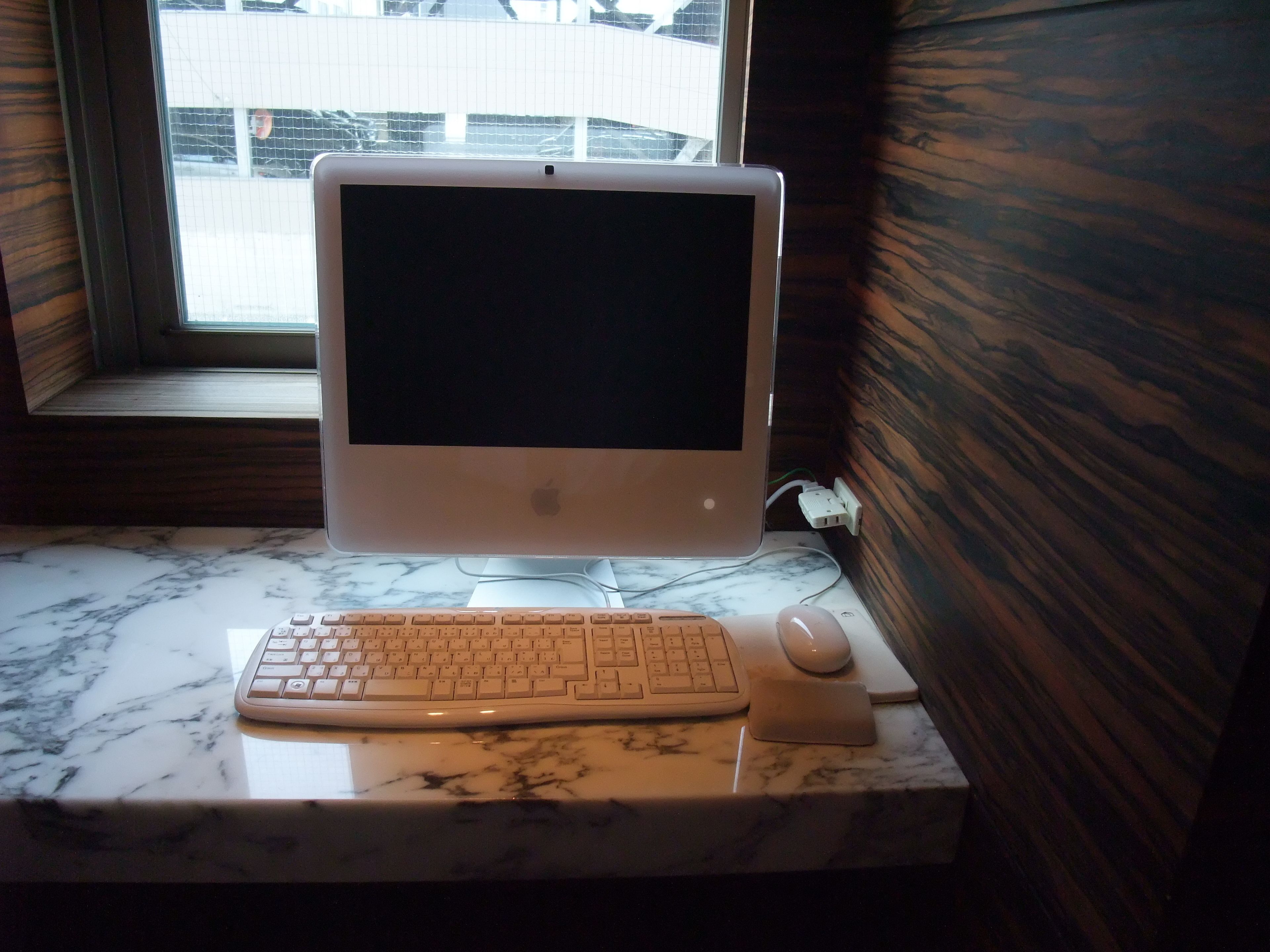 A desktop computer with a keyboard and mouse on a marble countertop.