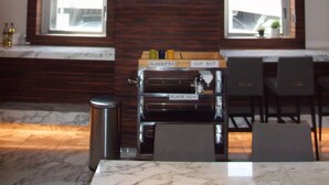 Cozinha moderna com forno embutido, máquina de café e resfriador de vinhos. Duas janelas oferecem iluminação natural e vista para a cidade.
