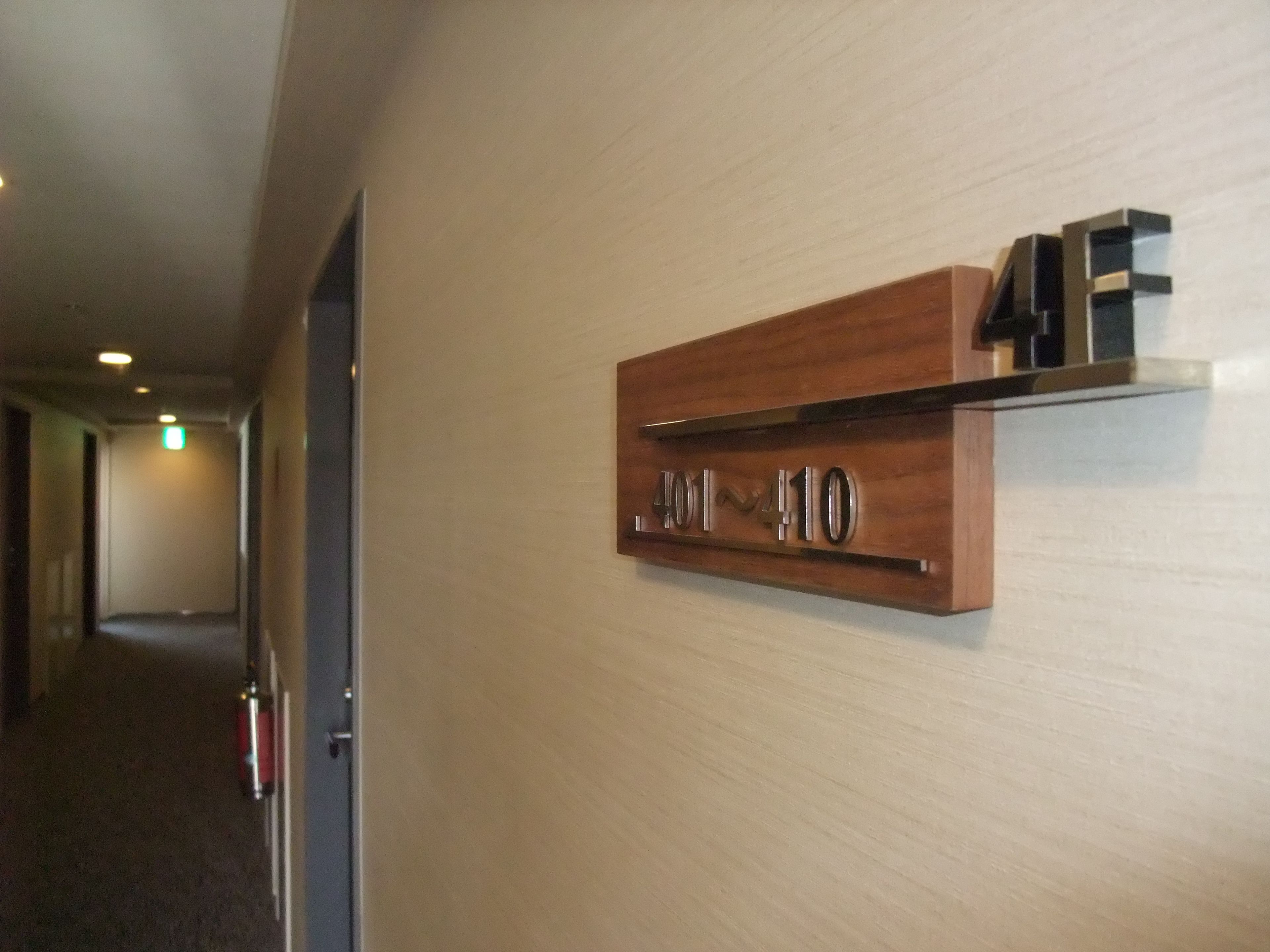 Un pasillo con un letrero de madera que muestra los números de habitación 401 al 410.